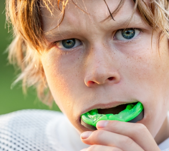 Young boy placing an athletic mouthguard over his teeth