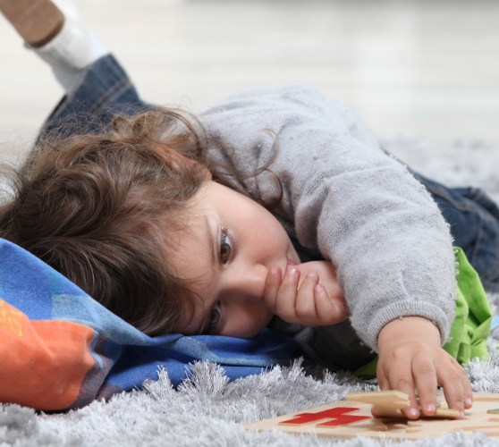 Toddler laying on the floor and sucking their thumb