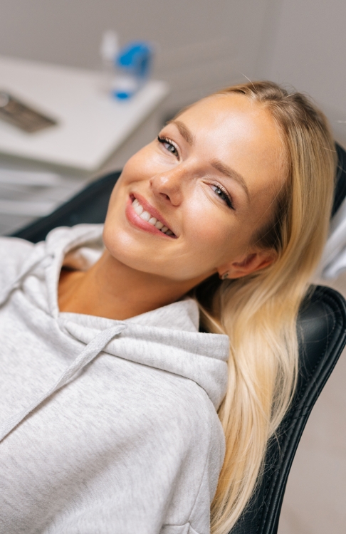 Woman leaning back in dental chair and smiling after cosmetic dentistry in Easton