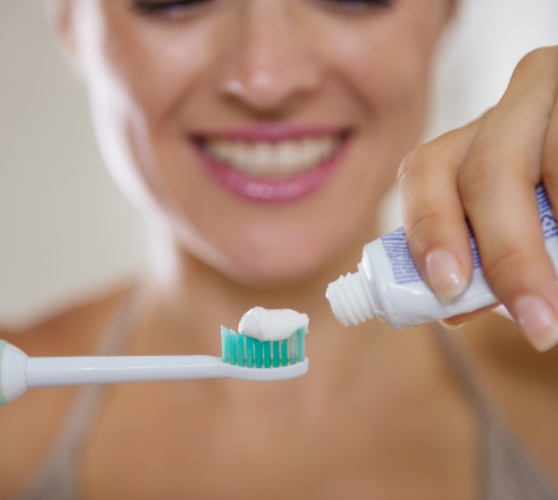 Person squeezing toothpaste onto a toothbrush