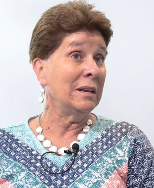 Woman in blue blouse wearing microphone while talking to interviewer