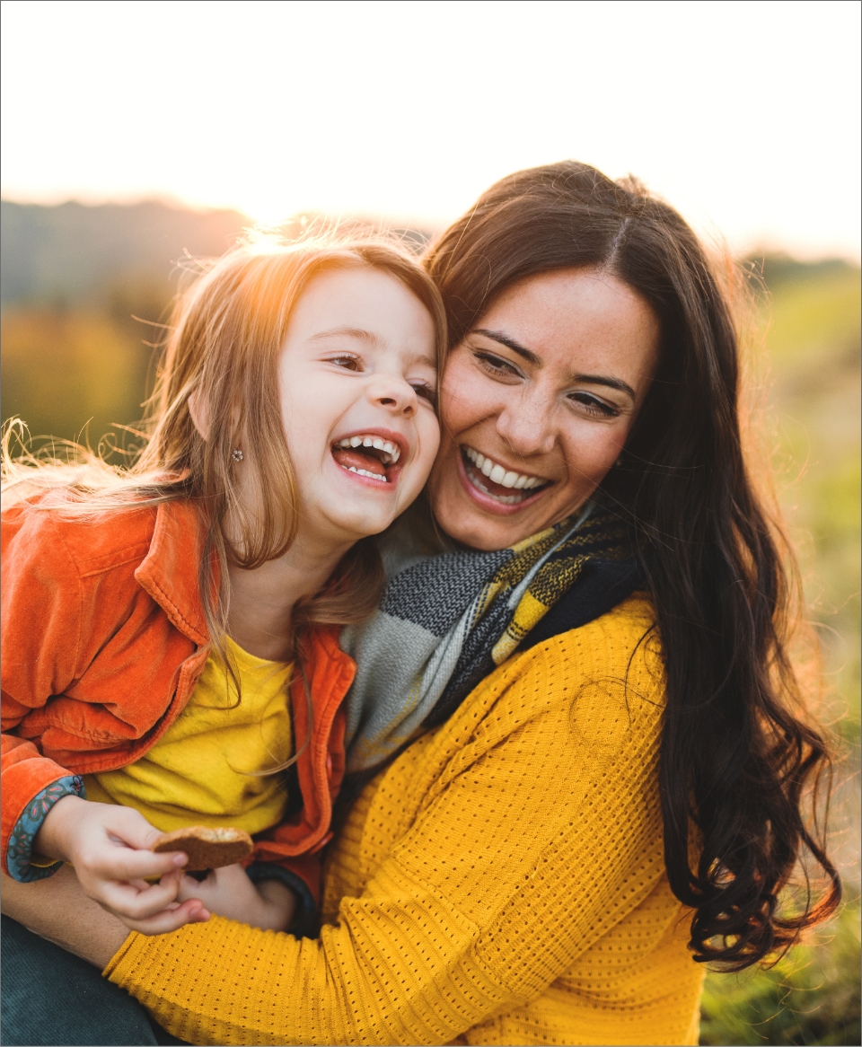 Smiling woman hugging her daughter outdoors