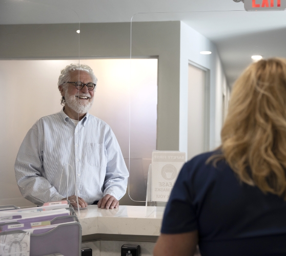 Senior man smiling at receptionist at Sound Dentistry