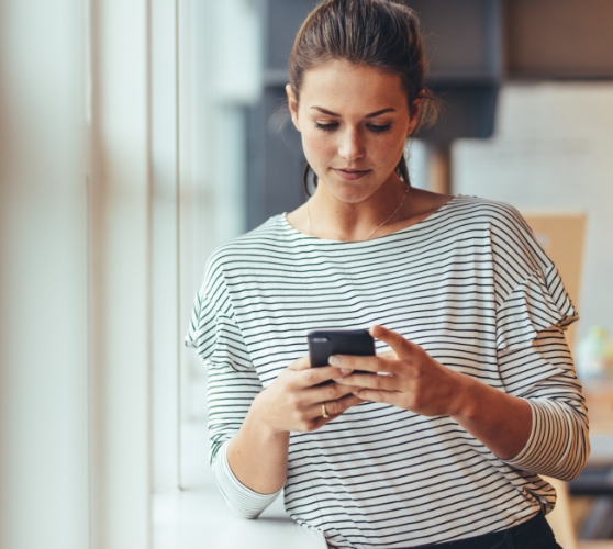 Woman standing and typing on her phone