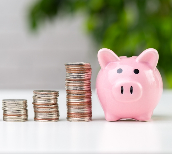 Three stacks of coins next to a pink piggy bank