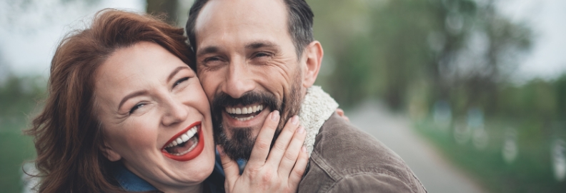 Man and woman smiling and hugging outdoors