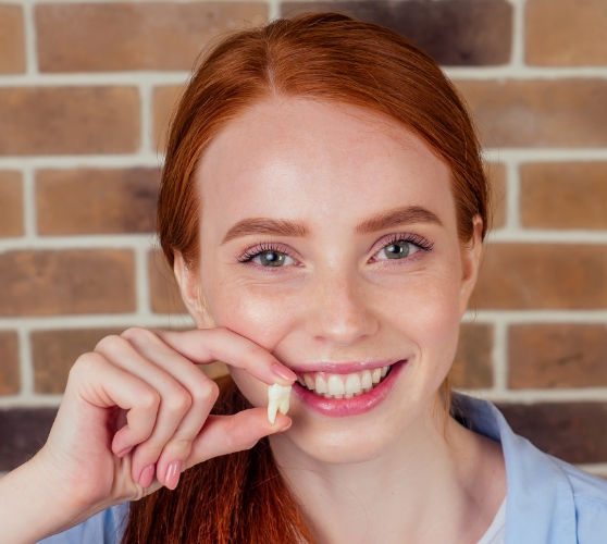 Smiling woman holding a tooth